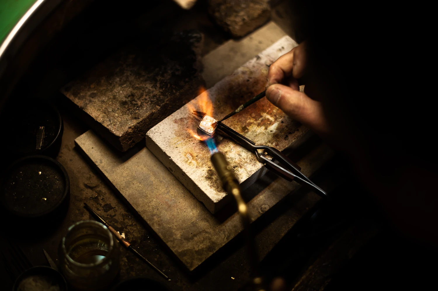 Orfebre trabajando con soplete en un taller a oscuras